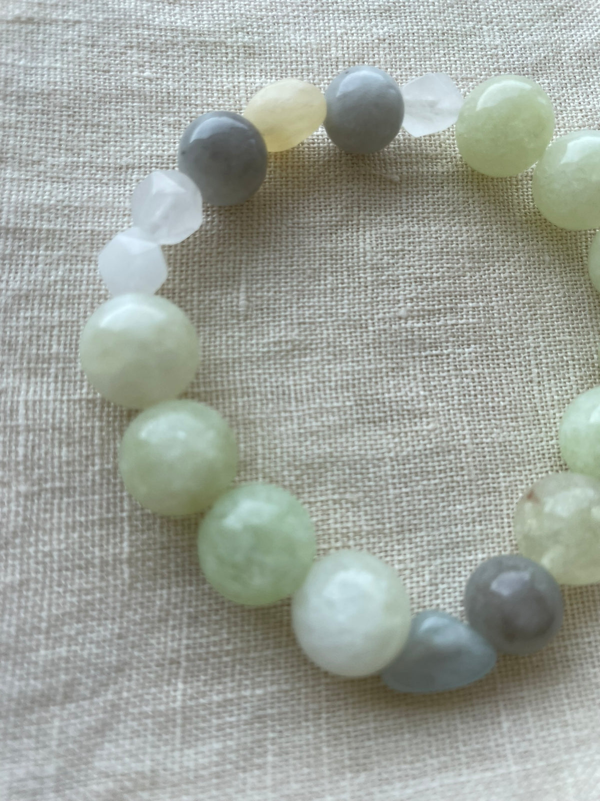 Close-up of the Serene Balance gemstone bracelet showing polished natural gemstones in soft green, blue and creamy white tones.