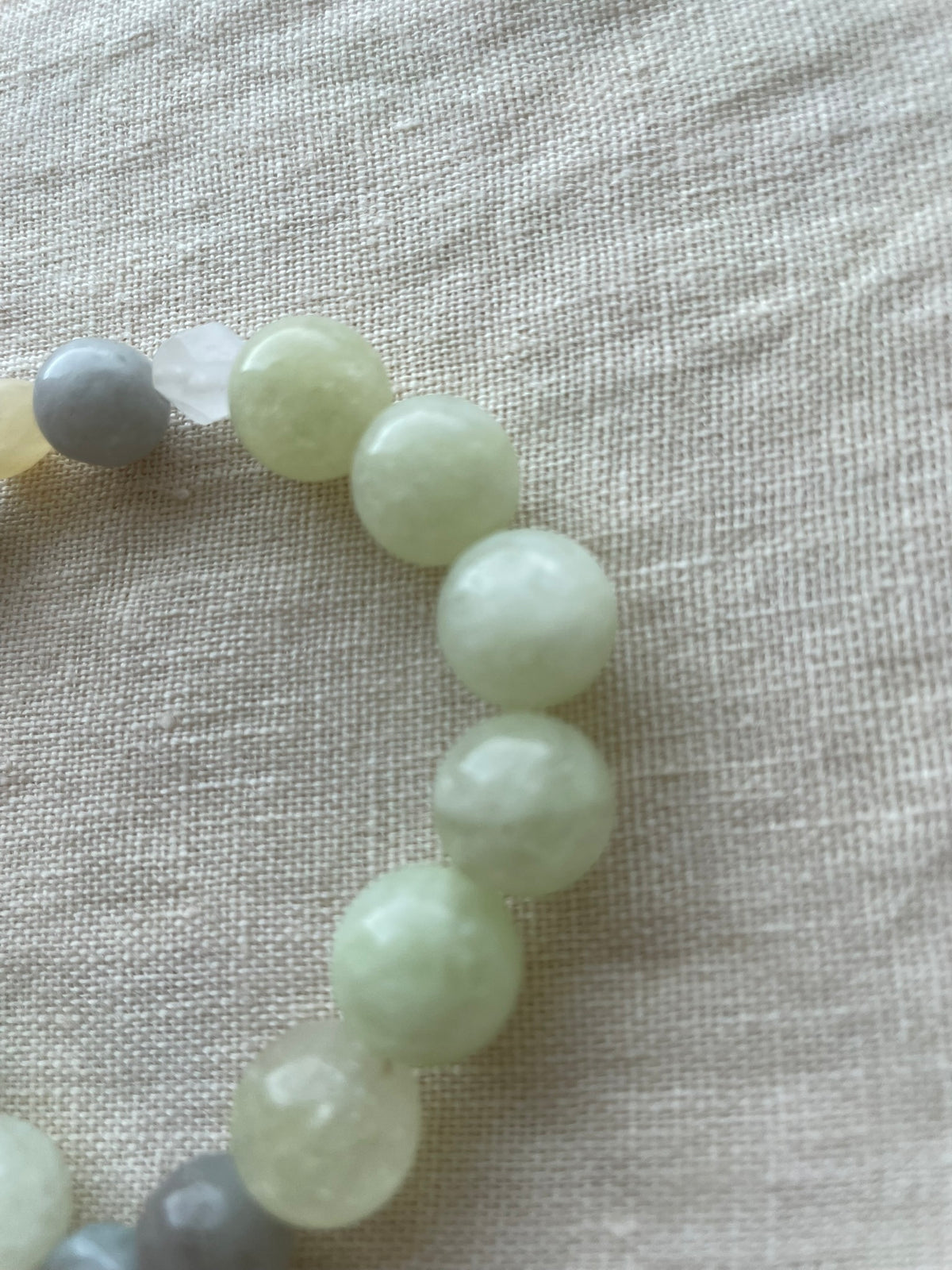 Close-up of Serene Balance natural gemstone bracelet with soft green and blue gemstones and creamy white accents.