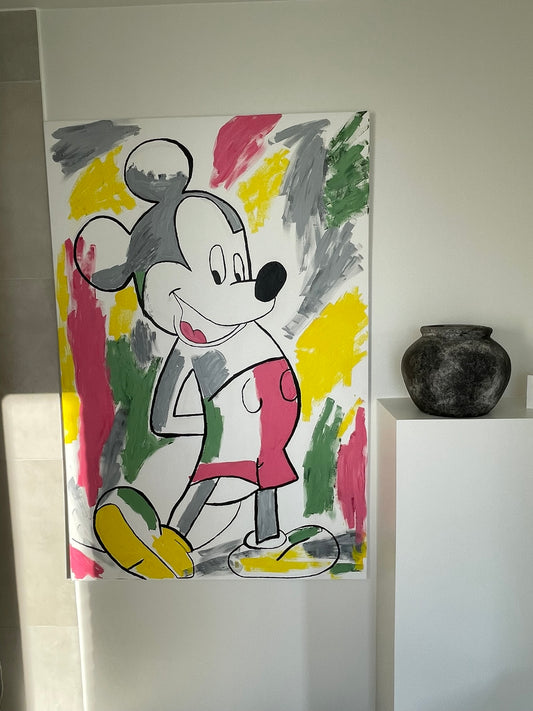 A colorful canvas painting of a cartoon mouse character in a white shirt and pink shorts, set against a background of abstract paint strokes in yellow, green, pink, and gray, displayed on a white wall next to a dark ceramic pot.