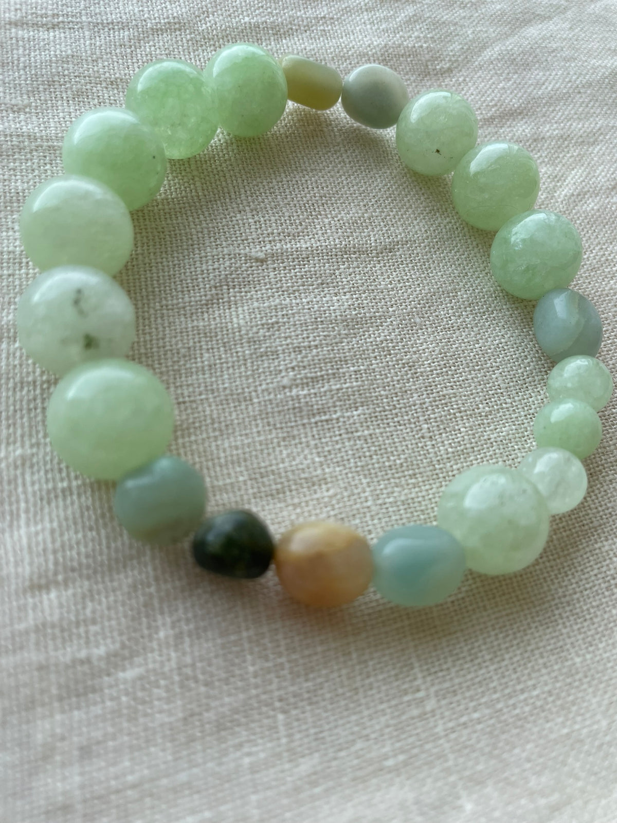 Close-up of the Green Harmony gemstone bracelet featuring polished natural green and blue-green gemstones.