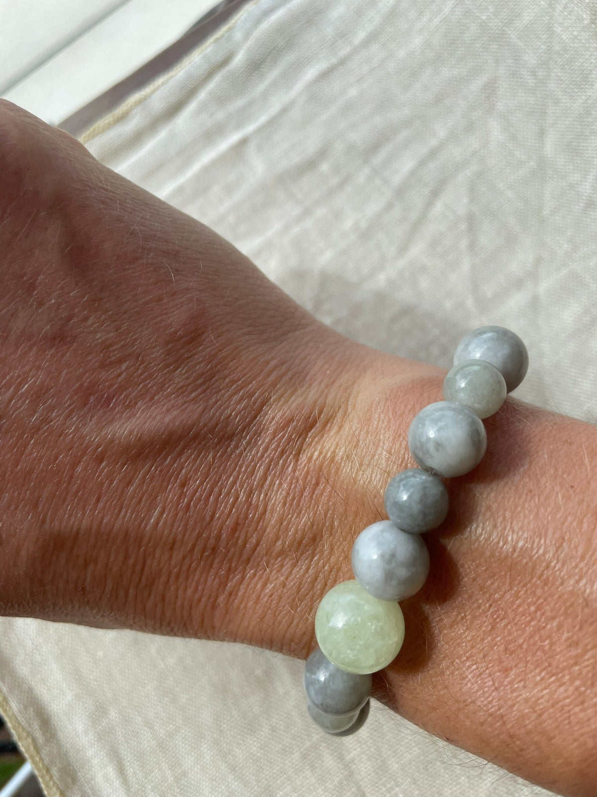 Handmade natural gemstone bracelet in soft ocean blue, misty grey and gentle green tones worn on the wrist.