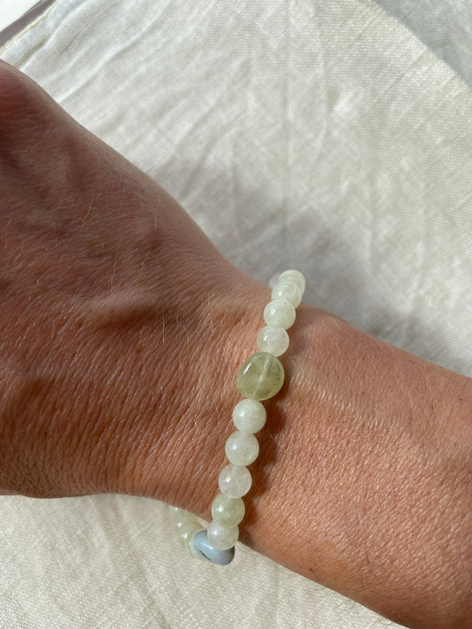 Handmade natural gemstone bracelet in soft meadow green, icy white and misty blue tones worn on the wrist.