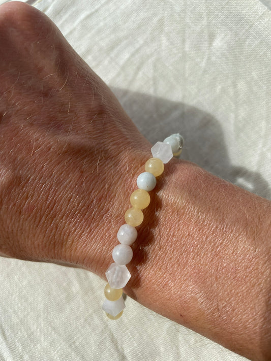 Handmade natural gemstone bracelet in ocean blue, soft white and earthy brown tones worn on the wrist.