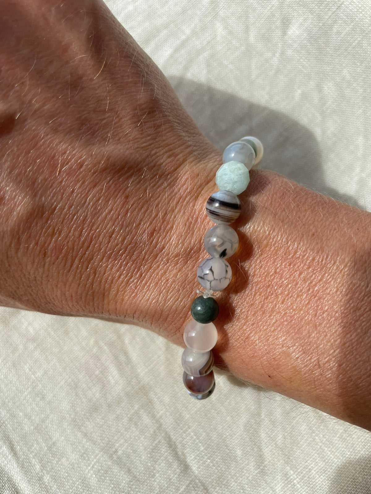 Forest Coast handmade gemstone bracelet worn on the wrist, showing its natural green, blue, white and earthy colour palette.