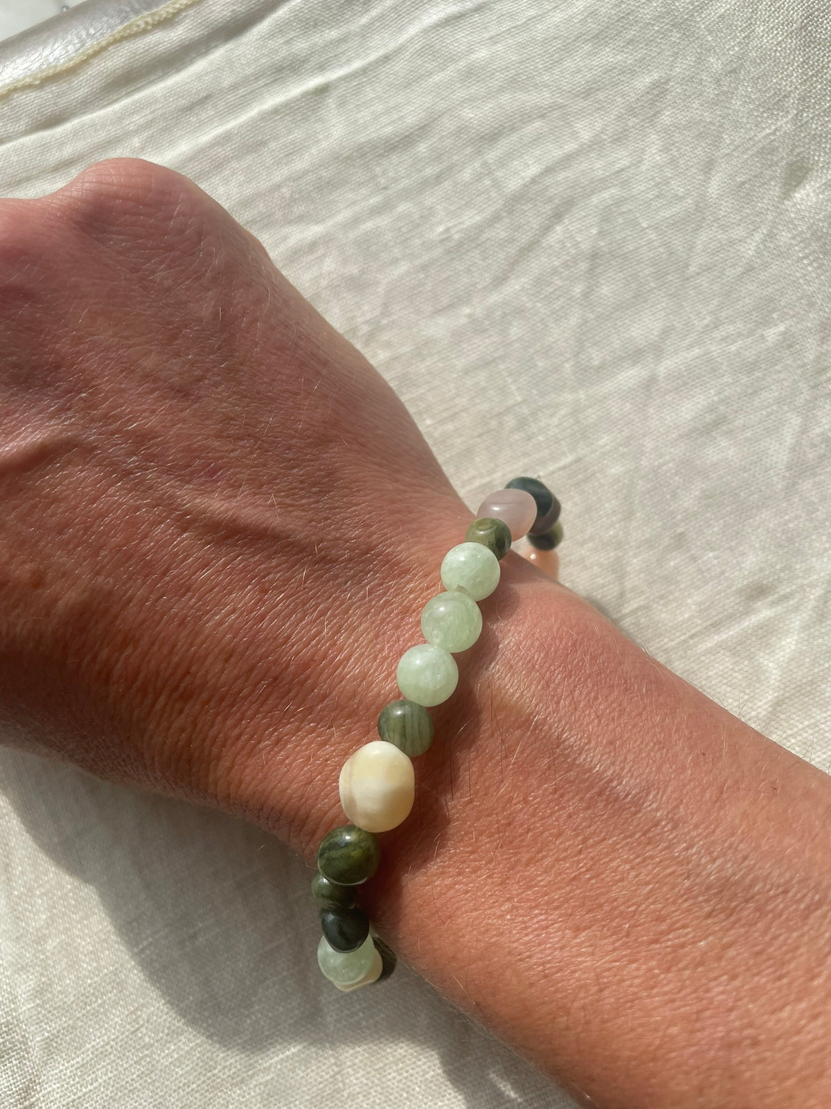 Close-up of the Forest Garden gemstone bracelet worn on the wrist, showing its soft green and natural earthy tones.